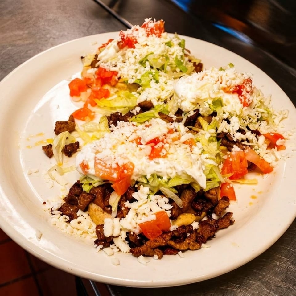 Three Santa Lucia Mexican Restaurant tacos with meat, lettuce, tomatoes, and cheese on a white plate.